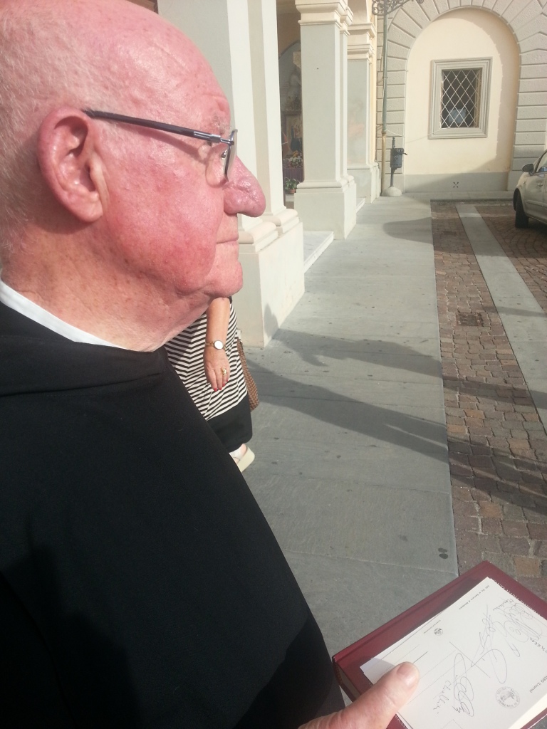 Padre Ildebrando con in mano gli autografi dei vip per i nipotini